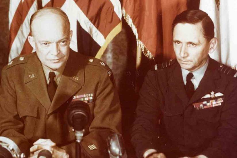 General of the Army Dwight D. Eisenhower, U.S. Army (left), and Air Chief Marshal Sir Arthur Tedder, Royal Air Force, address the world via motion picture and sound recordings shortly after the German mission signed the instrument of unconditional surrender in Reims, France, on May 7, 1945 (Naval History and Heritage Command)